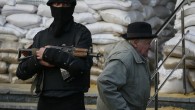 An elderly man passes by an armed man standing guard in front of barricades outside the mayor's office in Slaviansk
